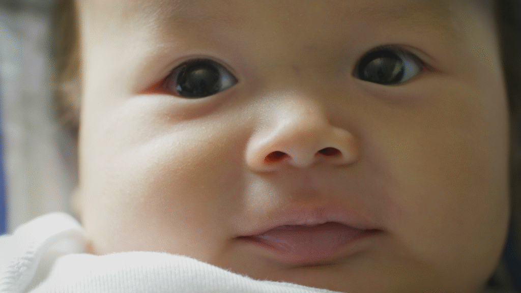 Close-up of a baby’s face with soft lighting, showing their eyes, nose, and mouth in gentle focus