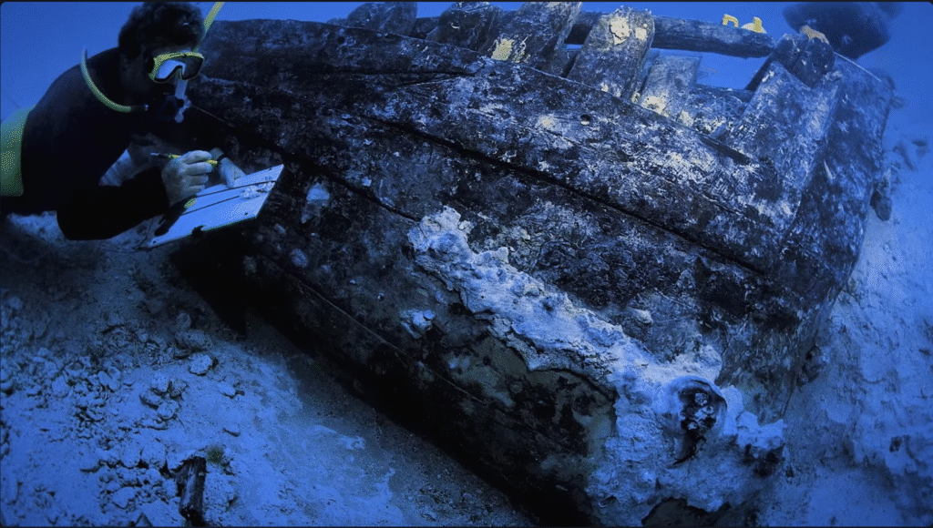 A diver examines an old shipwreck on the seabed